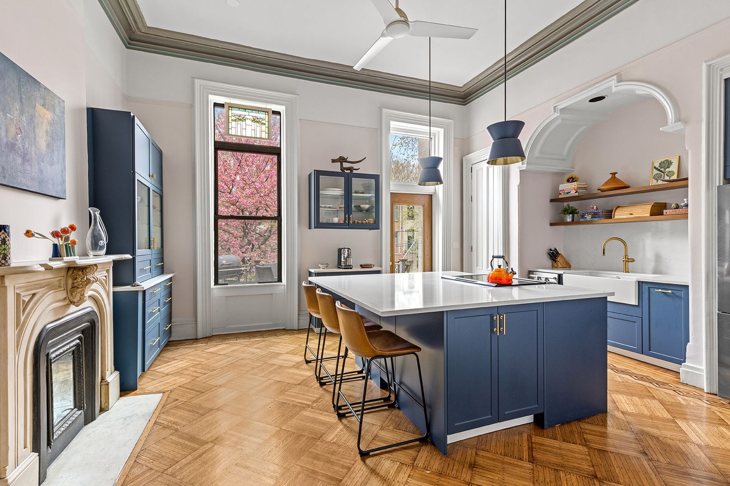 a room with stainless steel appliances a stove a refrigerator a sink dishwasher and wooden cabinets with wooden floor