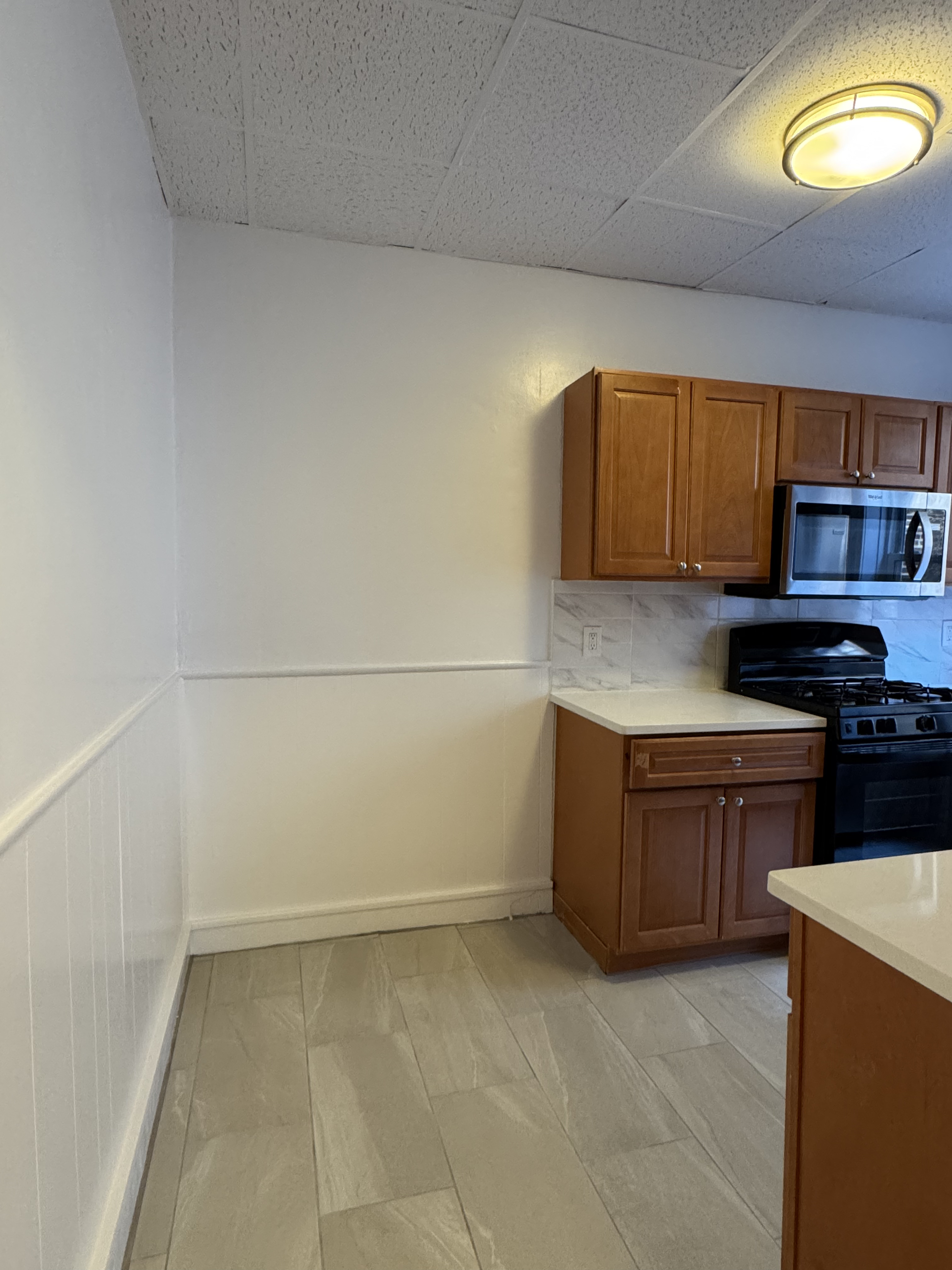 191-13 42nd Avenue, Unit 1F Queens, NY 11358 - Photo 5 of 6 a kitchen with granite countertop a stove a sink and a microwave