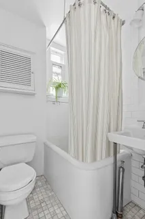 a white toilet sitting next to a small window