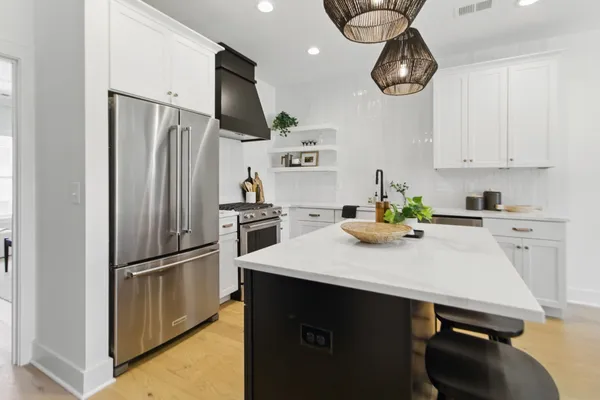 a kitchen with stainless steel appliances a refrigerator a sink a stove and white cabinets