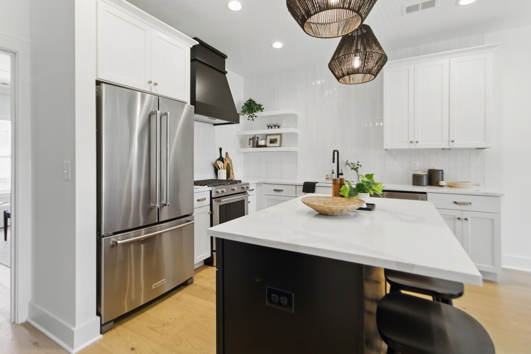 a kitchen with stainless steel appliances a refrigerator a sink a stove and white cabinets