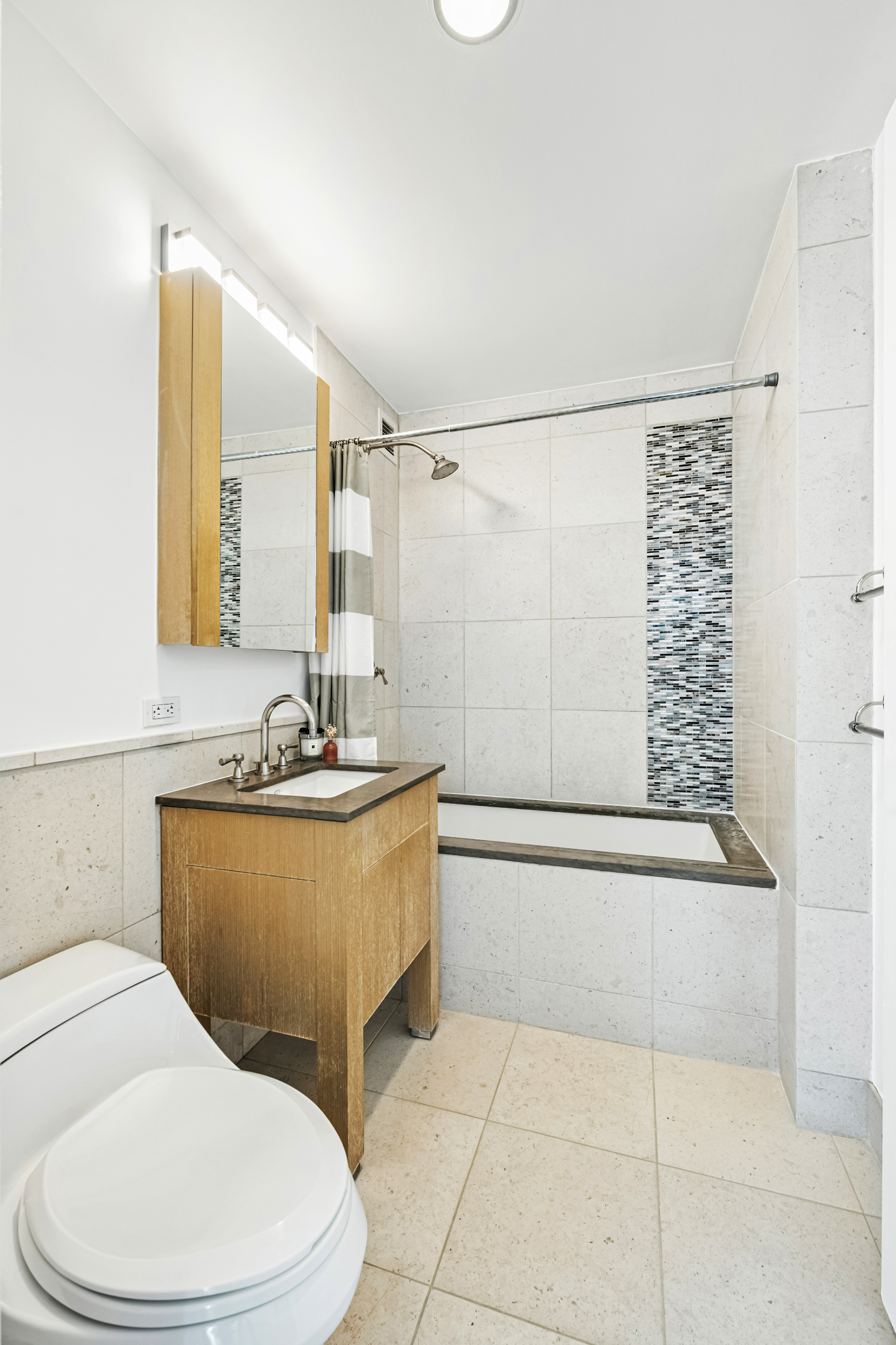 350 West 42nd Street, Unit 6K Manhattan, NY 10036 - Photo 7 of 13 a bathroom with a granite countertop bathtub sink vanity mirror and toilet