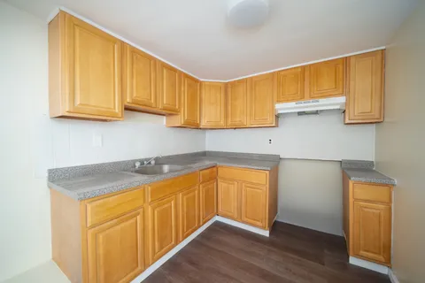 a kitchen with stainless steel appliances granite countertop wooden cabinets a sink and dishwasher with wooden floor