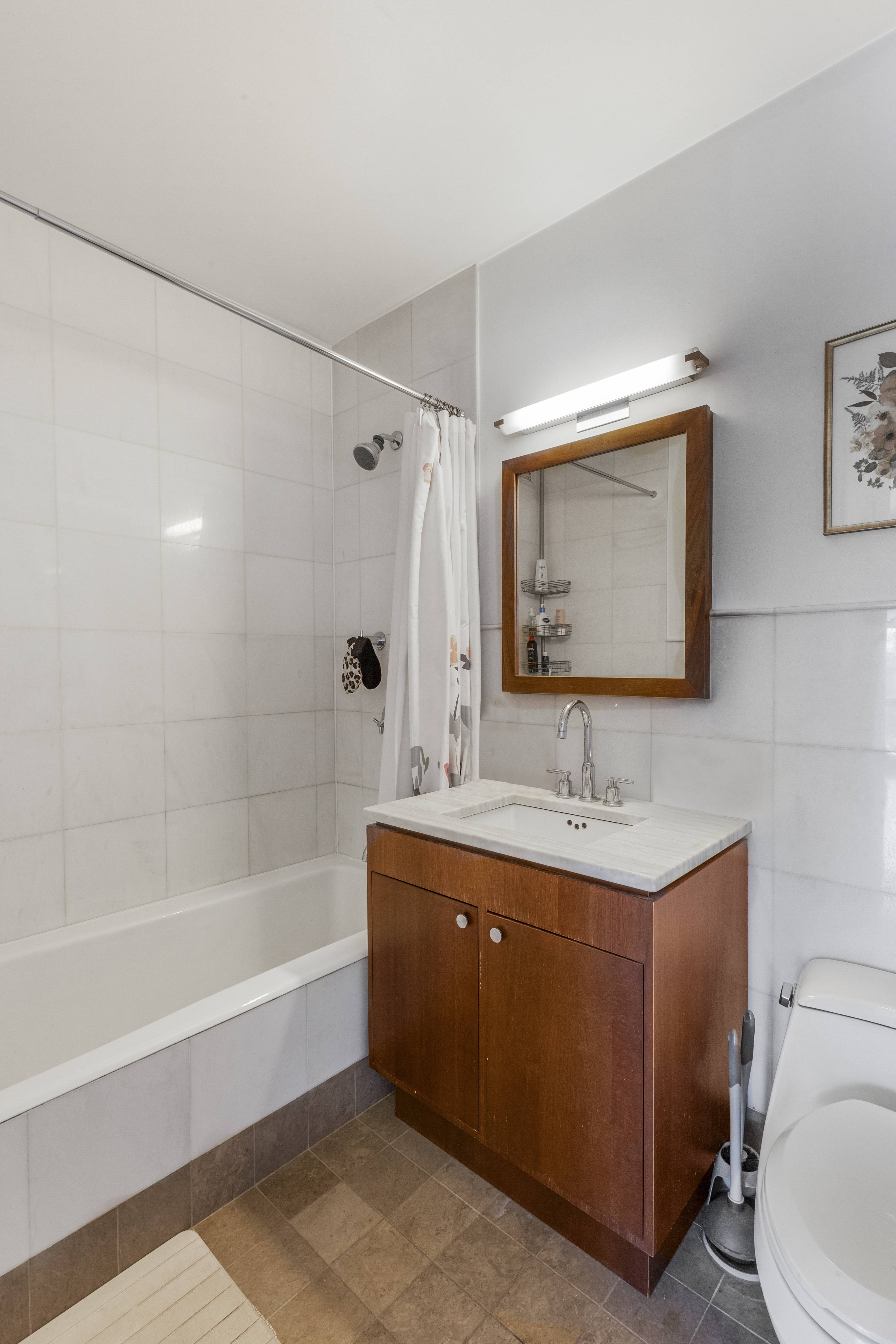 10 West End Avenue, Unit 7C Manhattan, NY 10023 - Photo 4 of 9 a bathroom with a toilet a sink a mirror and bathtub
