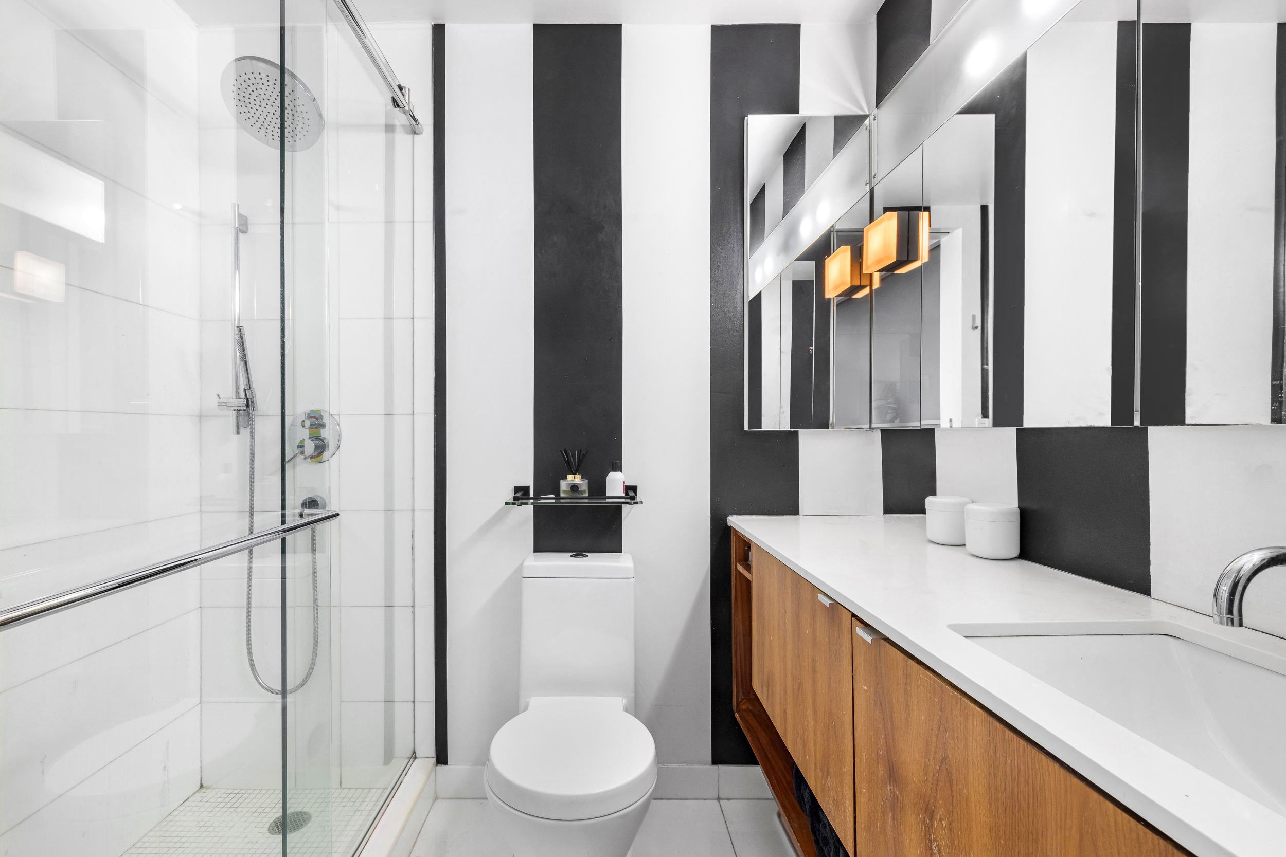 61 West 62nd Street, Unit 16D Manhattan, NY 10023 - Photo 7 of 11 a bathroom with a double vanity sink toilet and shower