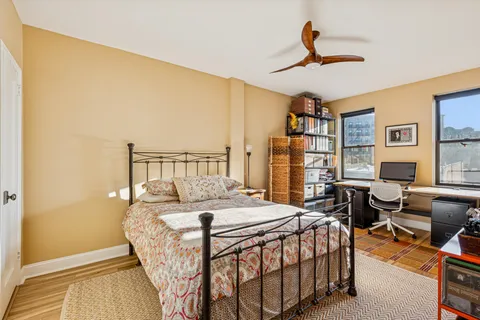 a bedroom with a bed a couch and a bookshelf with wooden floor