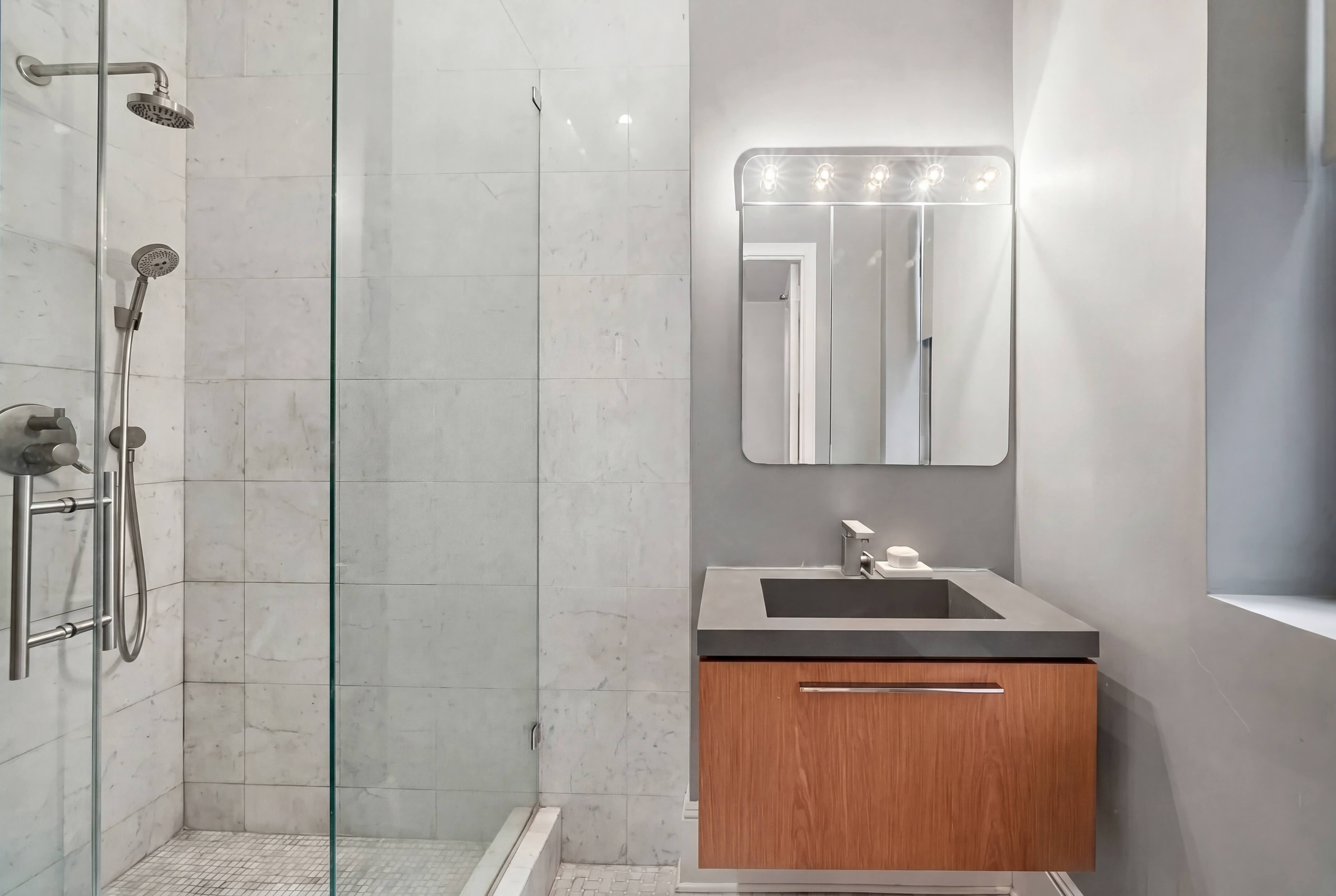 77 Park Avenue, Unit 6H Manhattan, NY 10016 - Photo 8 of 9 a bathroom with a granite countertop sink a mirror and shower