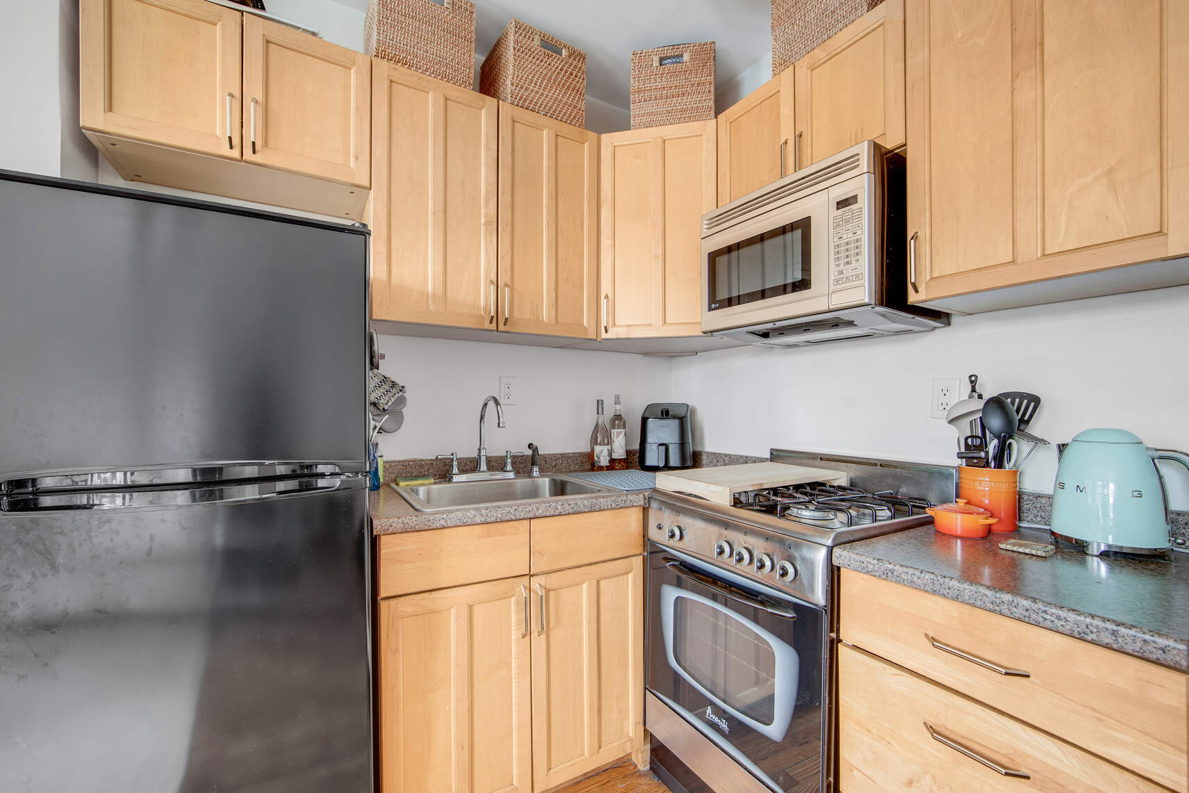 352 West 12th Street, Unit 5D Manhattan, NY 10014 - Photo 7 of 11 a kitchen with stainless steel appliances granite countertop a sink stove and microwave with wooden floor