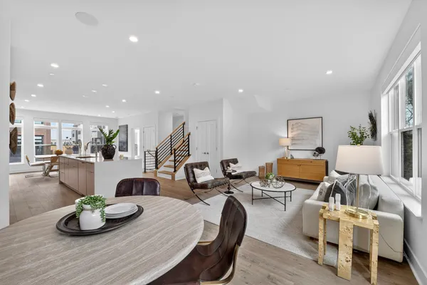 a living room with furniture kitchen view and a wooden floor