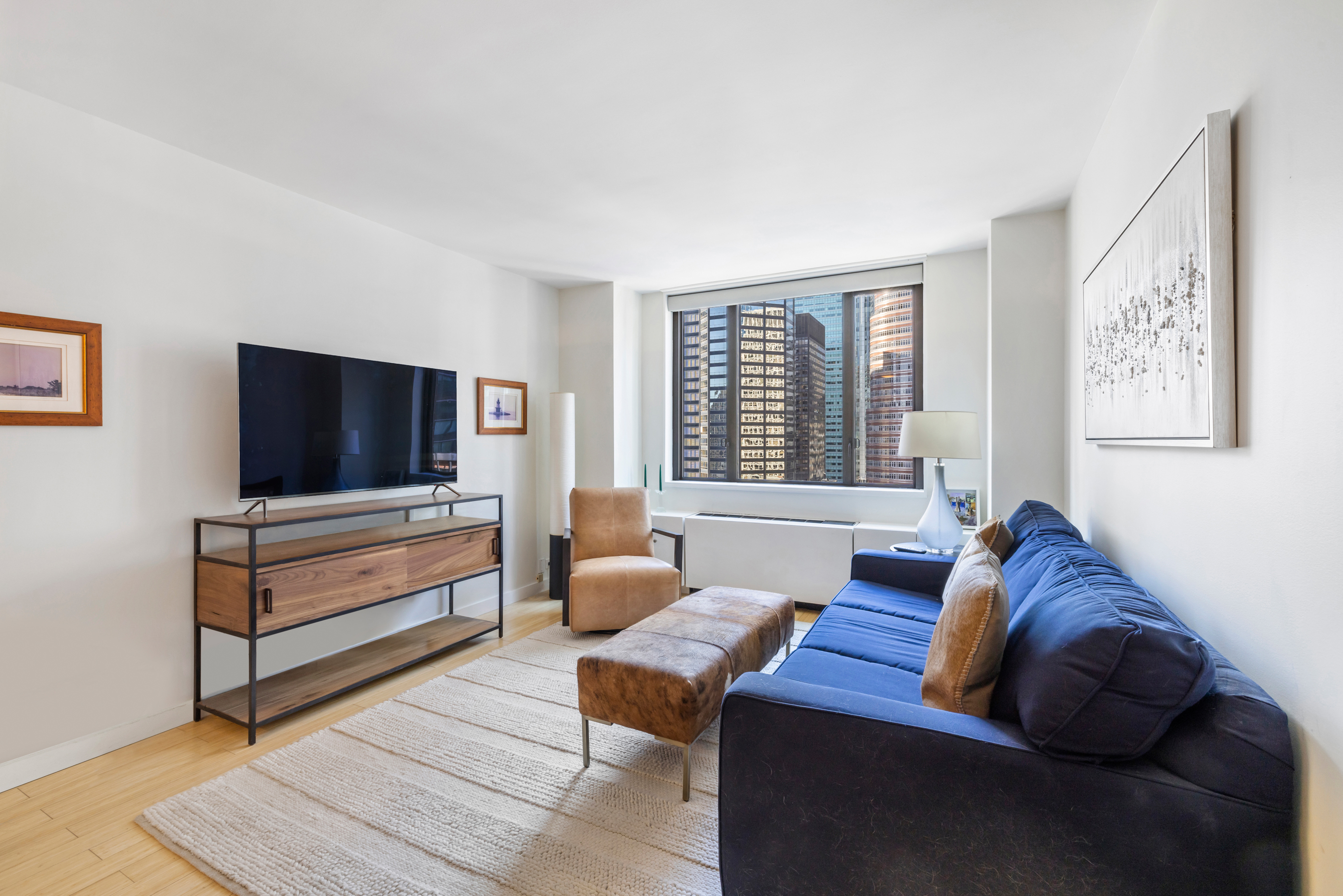 300 East 54th Street, Unit 23E Manhattan, NY 10022 - Photo 2 of 13 a living room with furniture and a flat screen tv