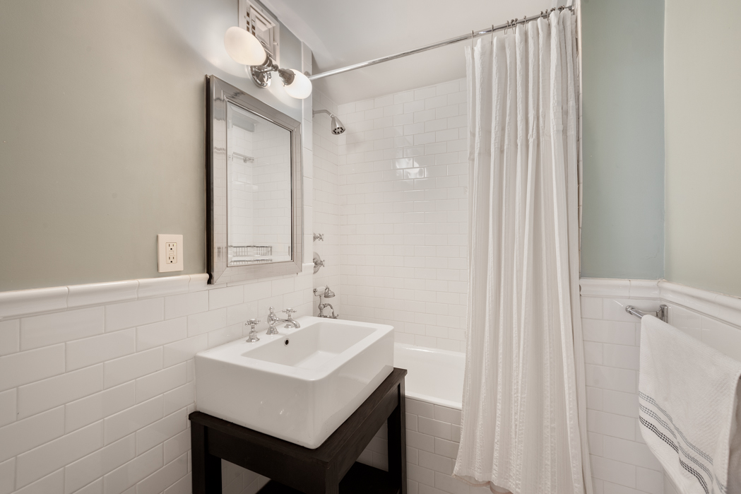 45 Tudor City Place, Unit 615 Manhattan, NY 10017 - Photo 4 of 5 a bathroom with a sink a mirror and a shower