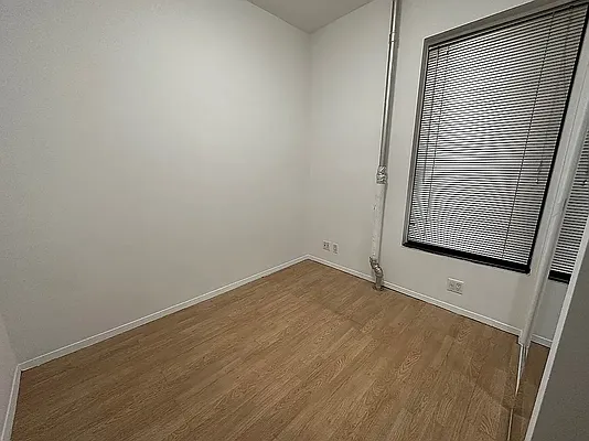 1313 3rd Avenue, Unit PH5 Manhattan, NY 10021 - Photo 4 of 5 a view of an empty room with wooden floor and a window