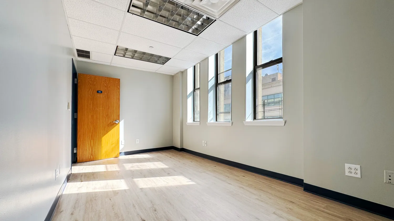 a view of an empty room with wooden floor and a window