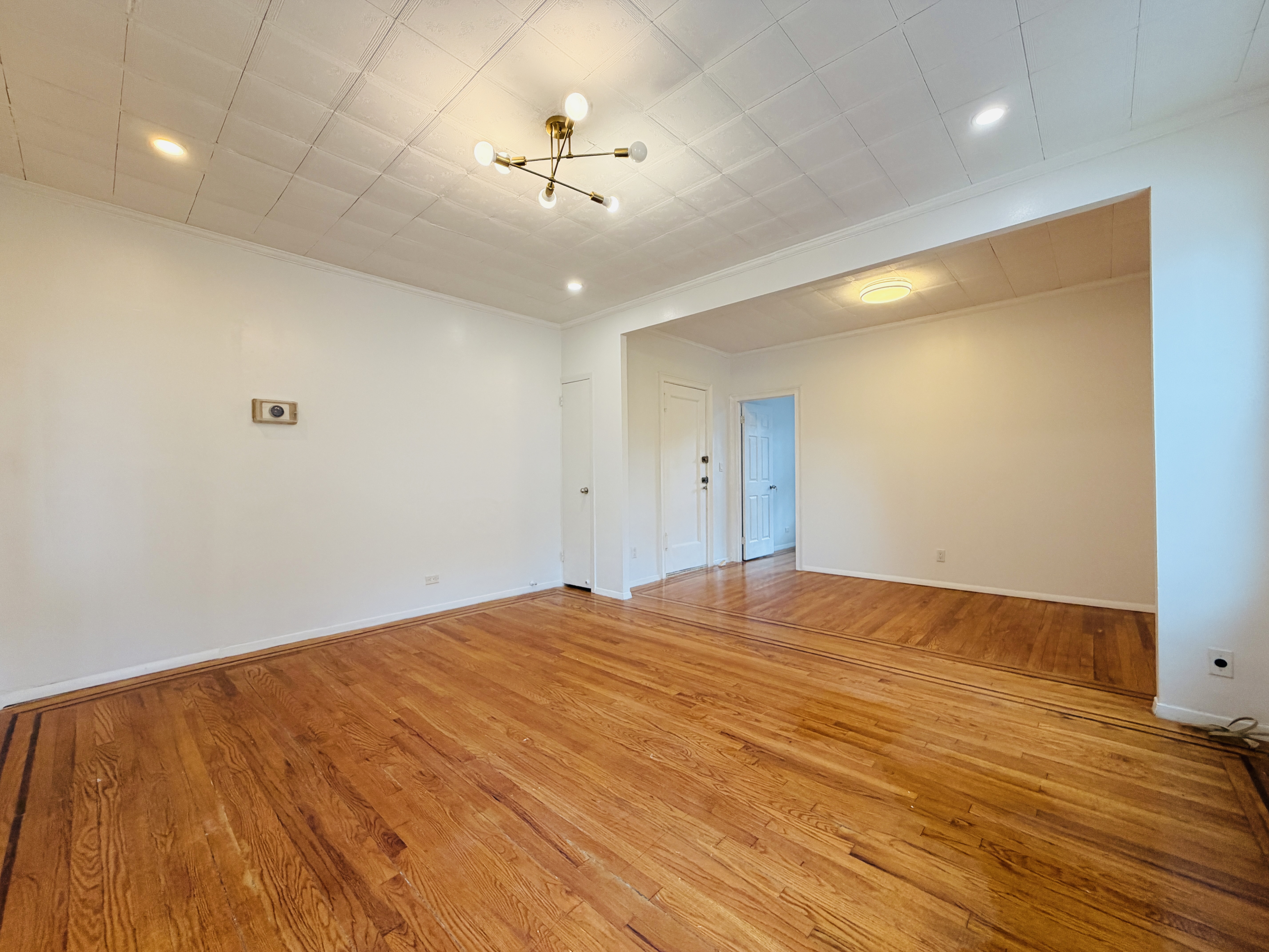 63-33 Haring Street, Unit 1F Queens, NY 11374 - Photo 4 of 13 a view of empty room with a fan and wooden floor