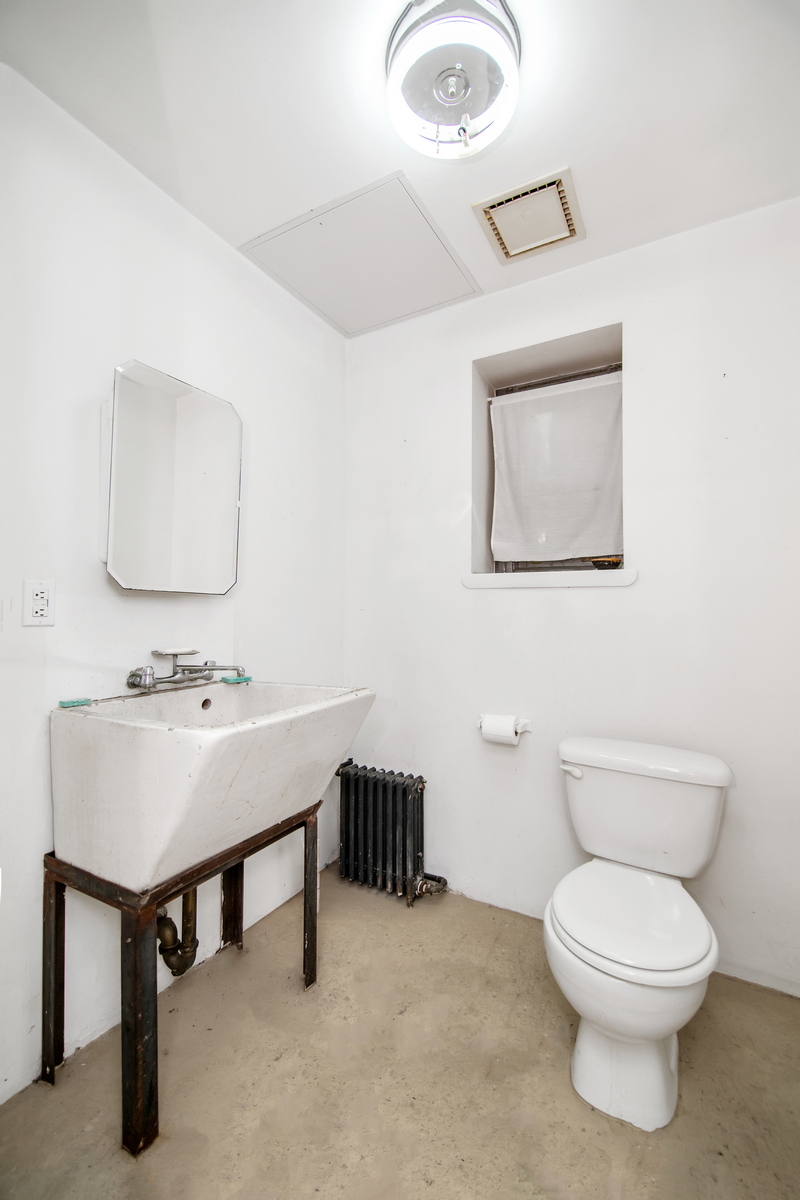 5-38 47th Road Queens, NY 11101 - Photo 12 of 14 a bathroom with a toilet a sink and mirror