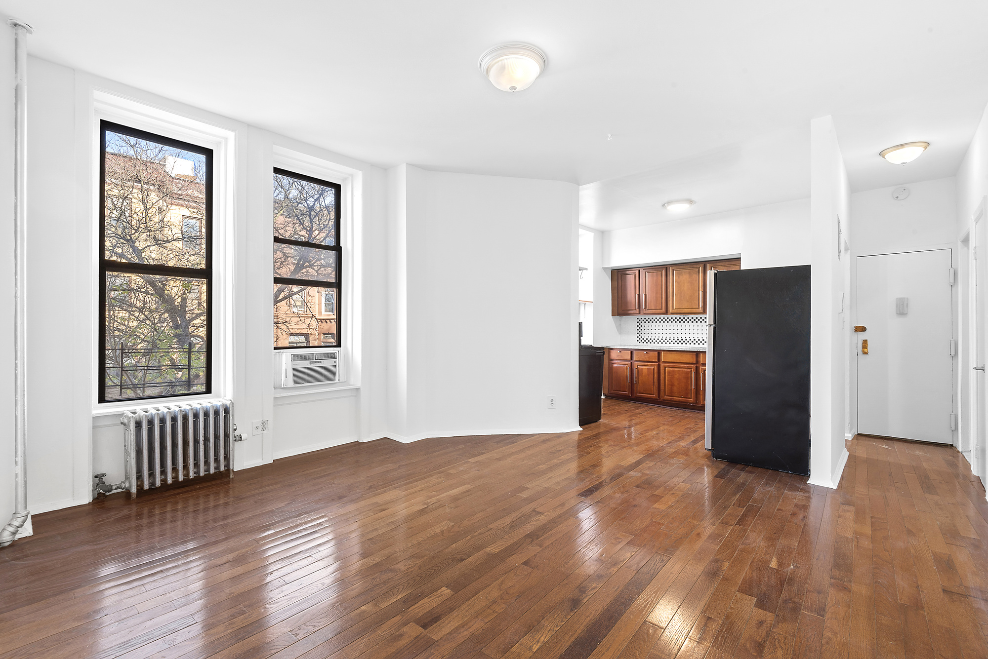 a view of an empty room with a window and wooden floor