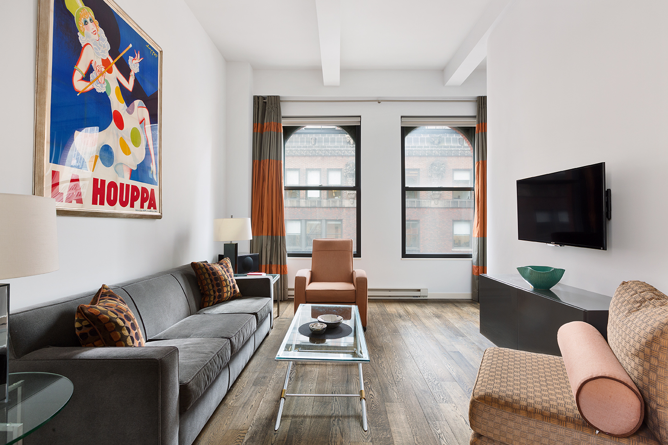 a living room with furniture a flat screen tv and a floor to ceiling window
