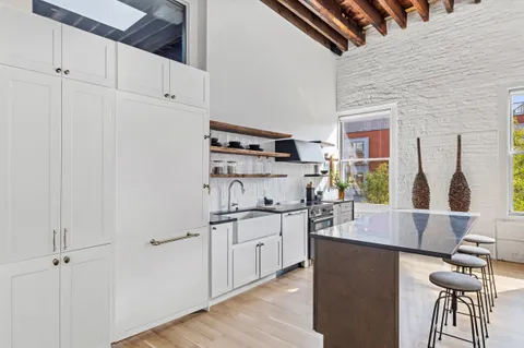 a living room with stainless steel appliances kitchen island granite countertop a refrigerator and a stove top oven