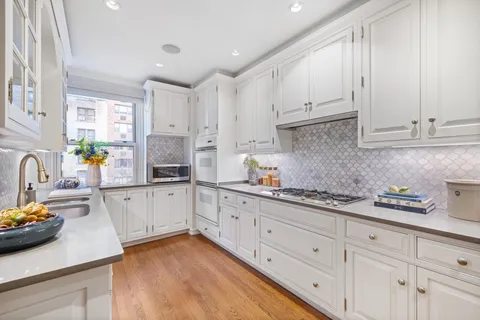 a kitchen with granite countertop white cabinets white appliances and a sink