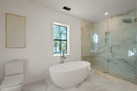 a bathroom with a white bath tub sitting next to a shower