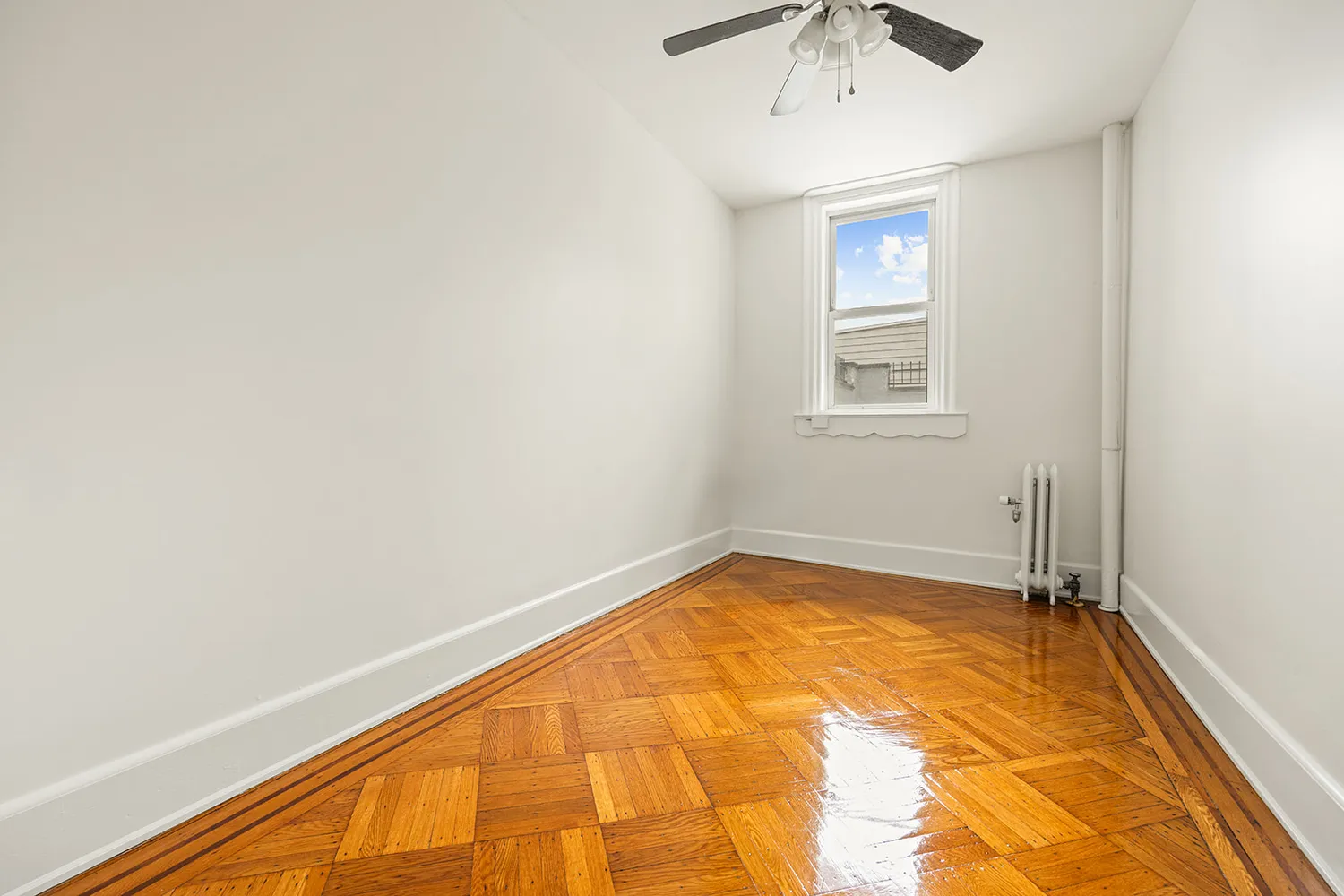a view of a room with a wooden floor and a chandelier fan