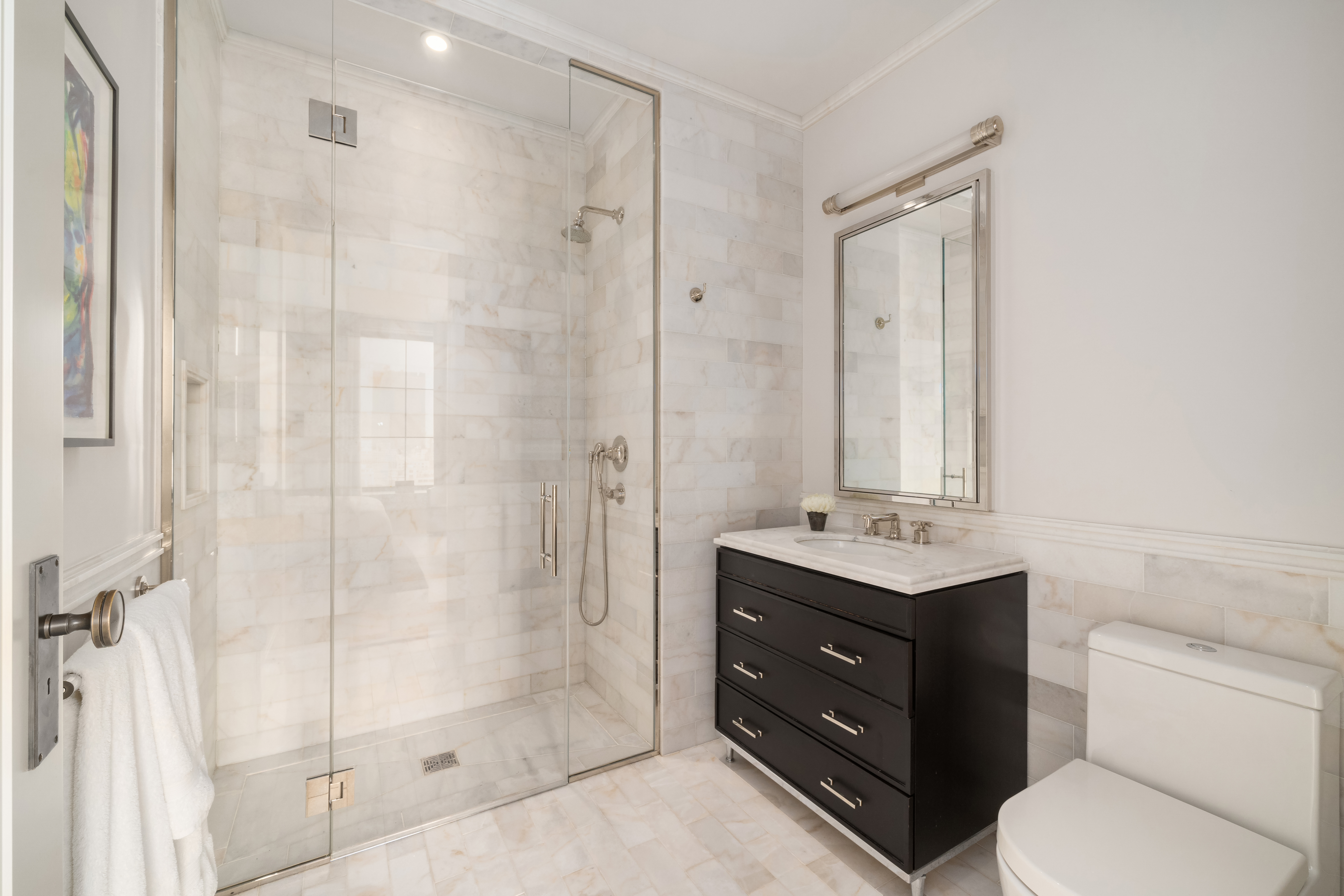 212 West 18th Street, Unit 19C Manhattan, NY 10011 - Photo 14 of 27 a bathroom with a toilet a sink and glass door