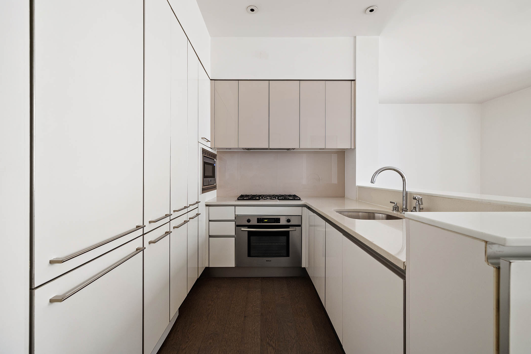 25 Broad Street, Unit 16I Manhattan, NY 10004 - Photo 7 of 23 a kitchen with white cabinets and white appliances