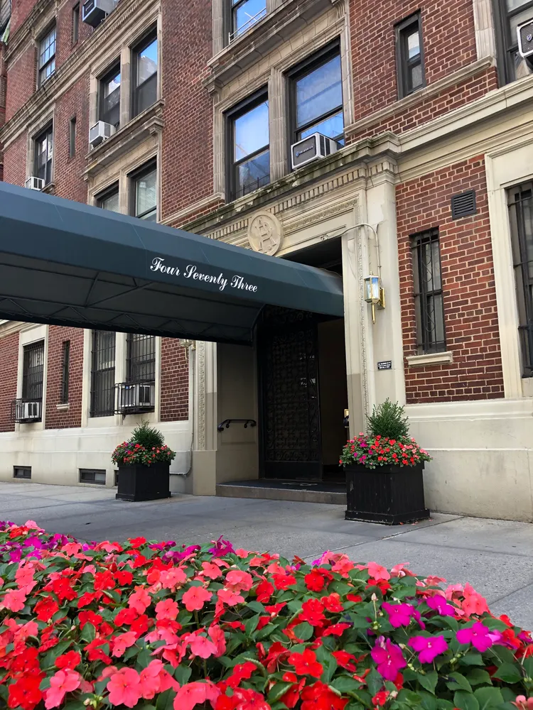 a front view of building with beautiful flowers and flowers
