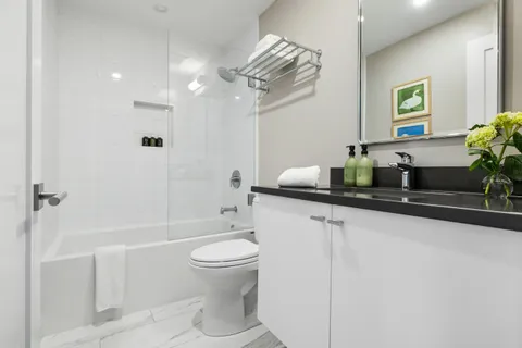 a bathroom with a granite countertop sink a toilet a mirror and shower