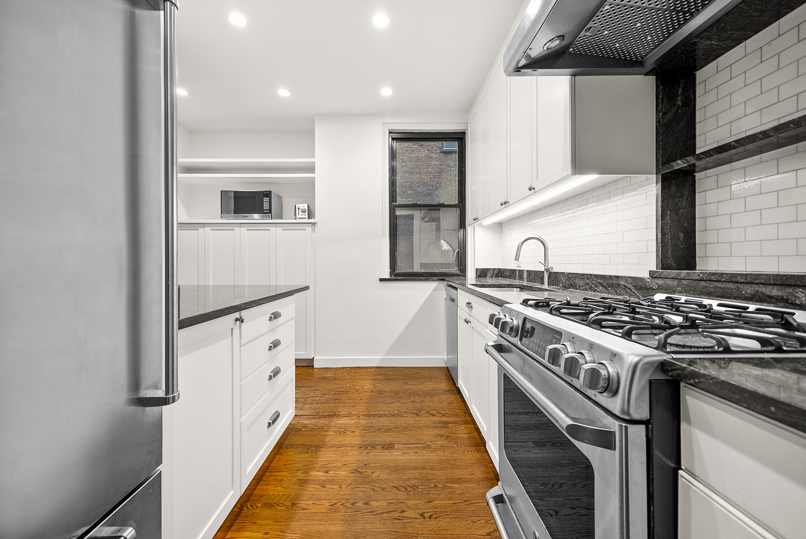 152 West 58th Street, Unit 6CD Manhattan, NY 10019 - Photo 6 of 9 a kitchen with granite countertop a stove and a refrigerator
