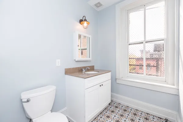 a bathroom with a granite countertop sink toilet and mirror
