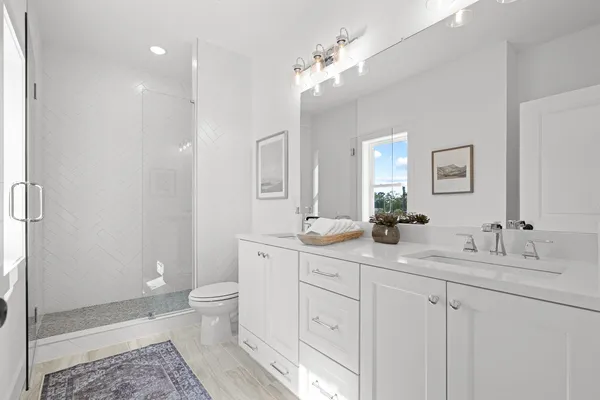 a spacious bathroom with double vanity a toilet a and a shower