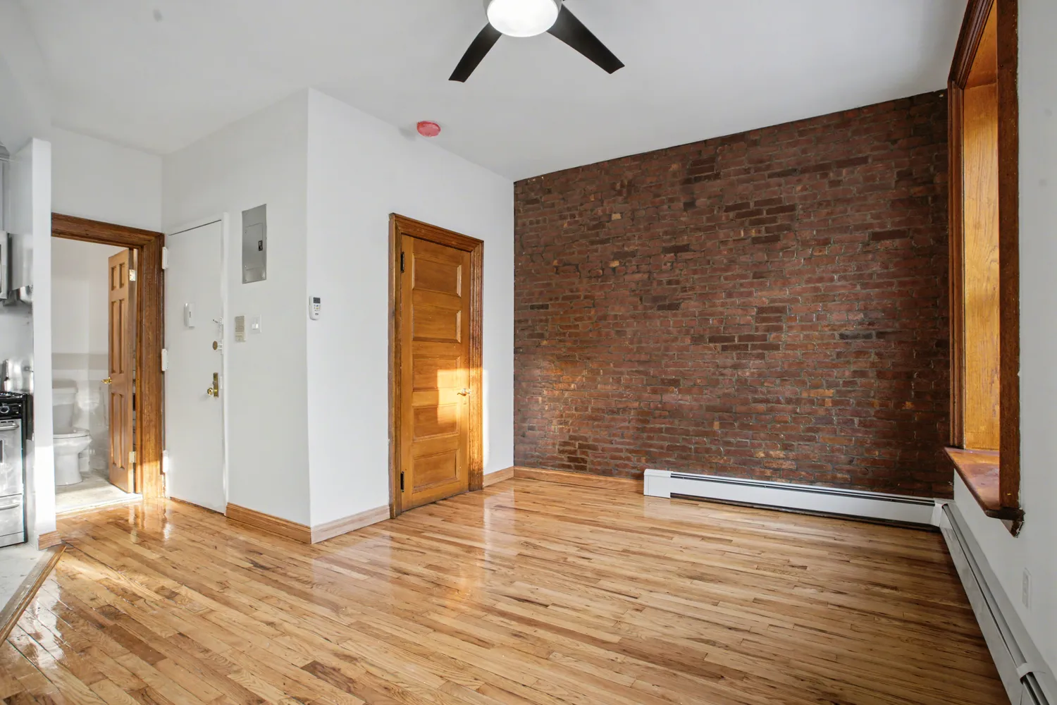 a view of an empty room with wooden floor and a window