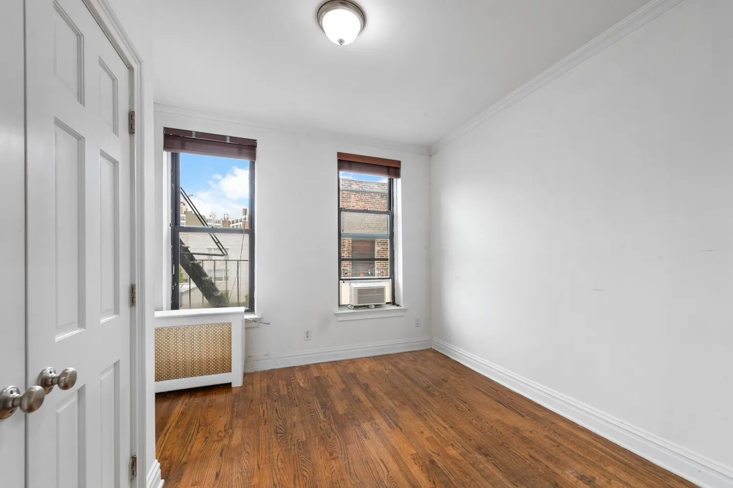 an empty room with wooden floor cabinet and windows
