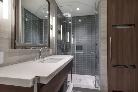 a bathroom with a sink a toilet a mirror and shower