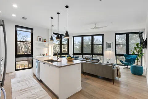 a living room with stainless steel appliances granite countertop sink stove and wooden floor
