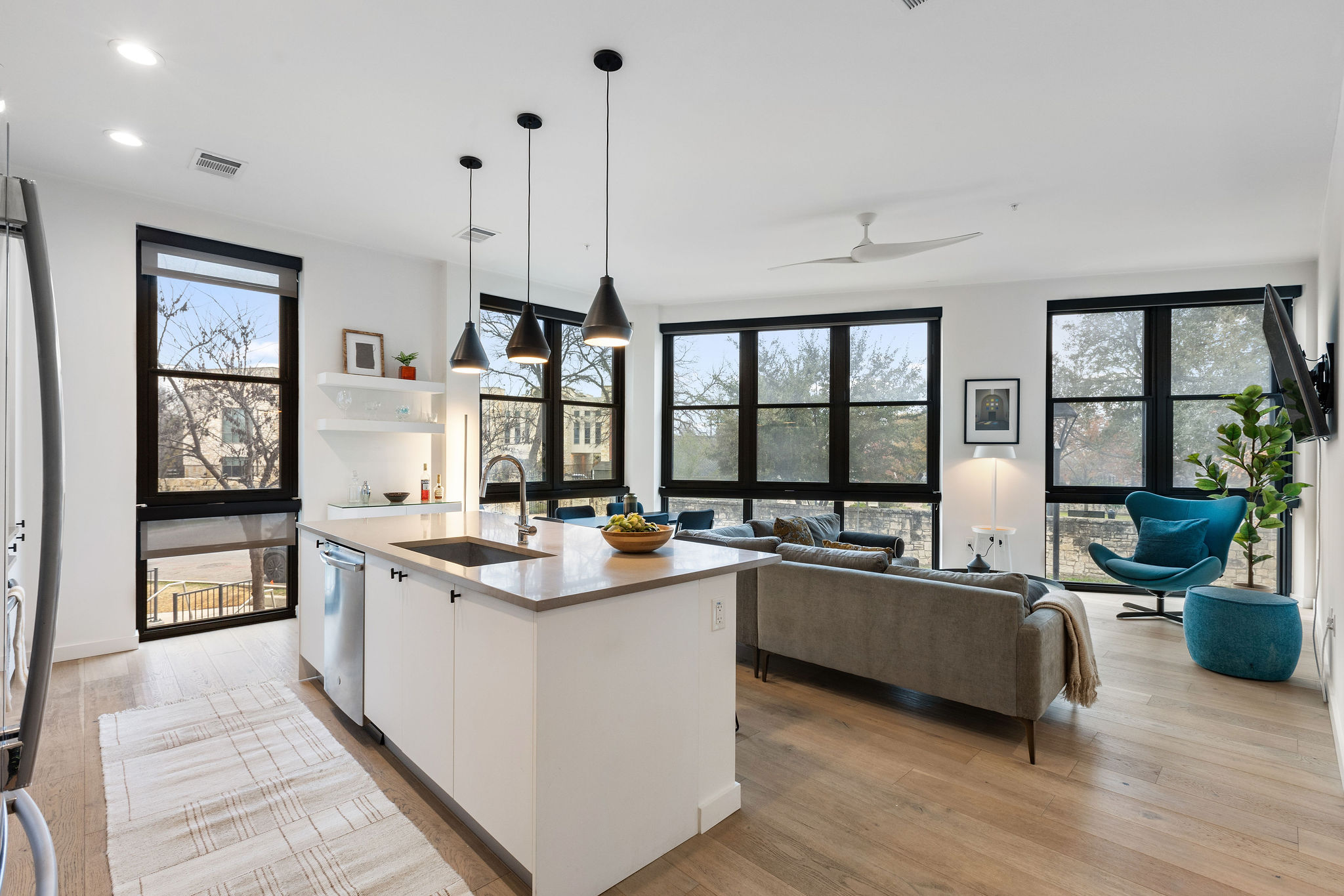 a living room with stainless steel appliances granite countertop sink stove and wooden floor