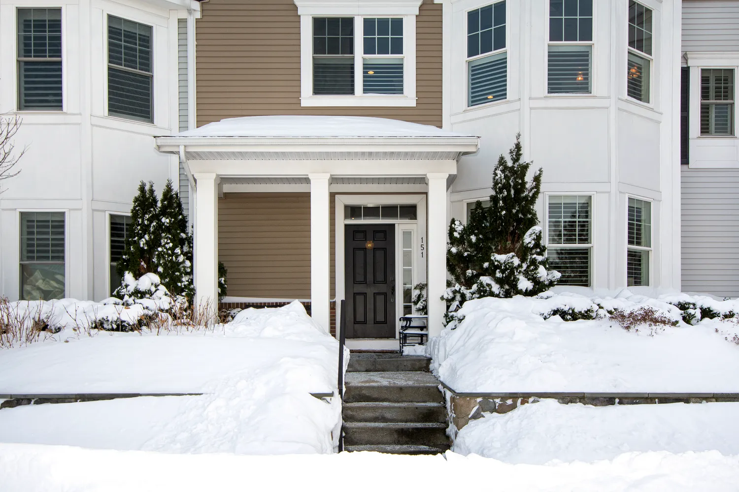 a view of a house with potted plants and a bench in front of door
