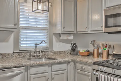 a kitchen with granite countertop white cabinets and a sink