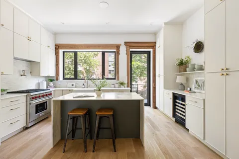 a kitchen with kitchen island a stove a sink a dining table and chairs