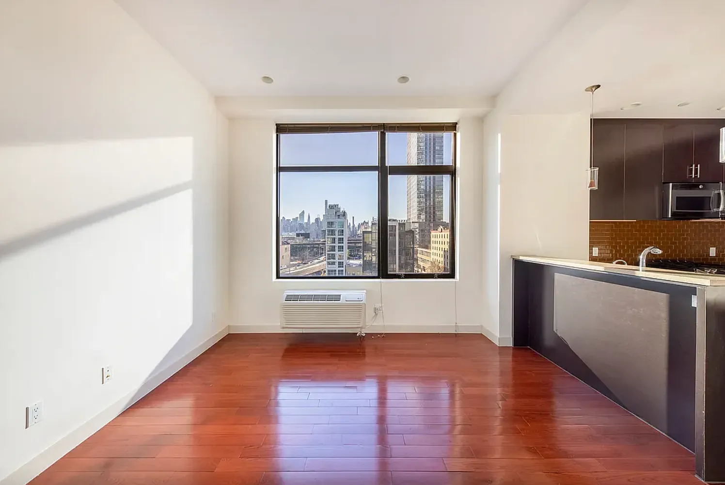a view of an empty room with window and wooden floor