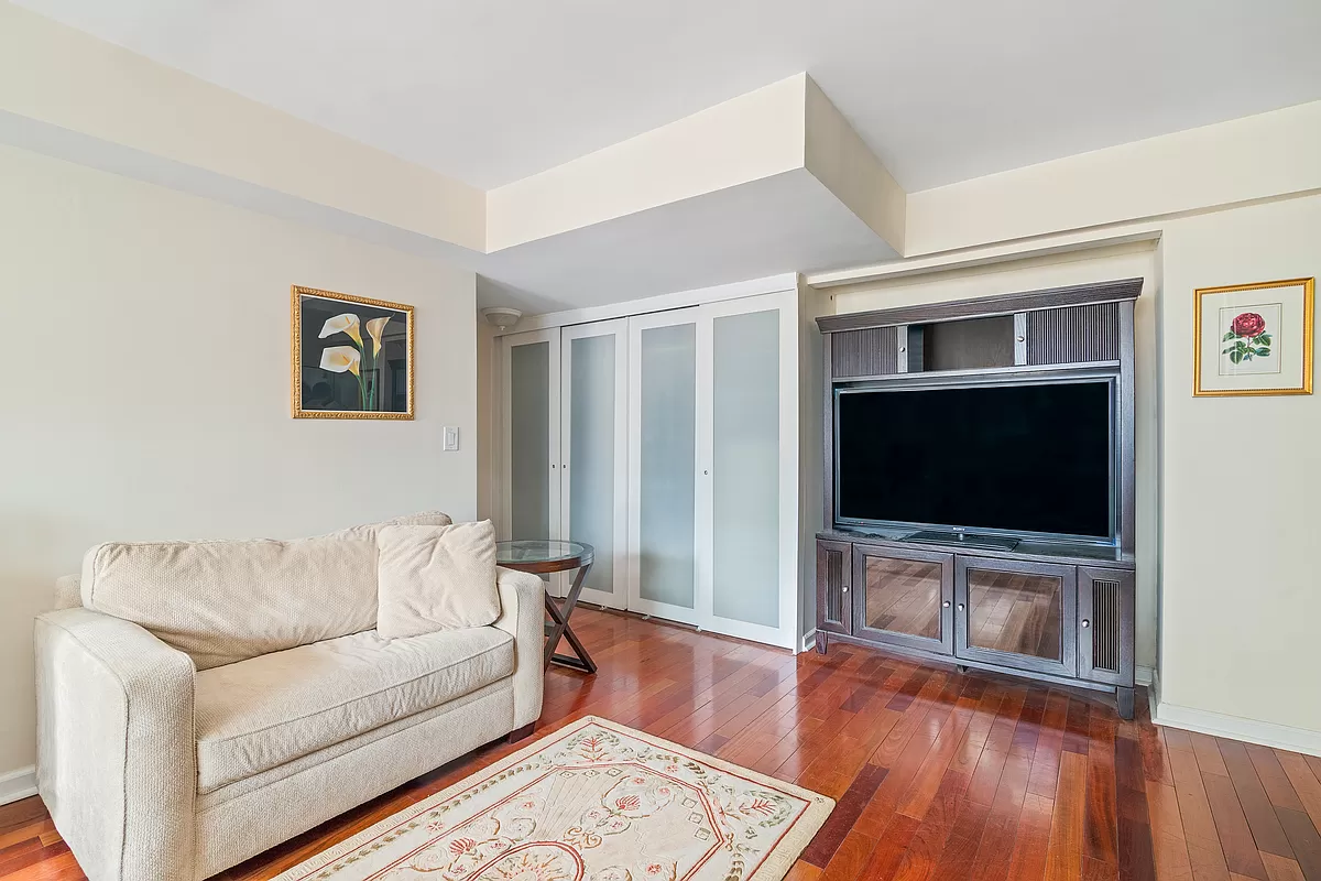 153 East 57th Street, Unit 17F Manhattan, NY 10022 - Photo 2 of 8 a living room with furniture and a flat screen tv