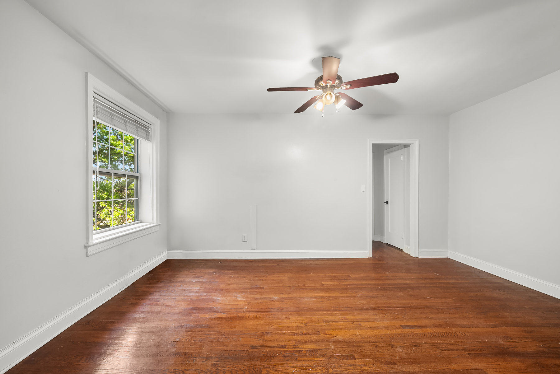 30-31 Hobart Street, Unit 3L Queens, NY 11377 - Photo 5 of 14 an empty room with wooden floor ceiling fan and windows