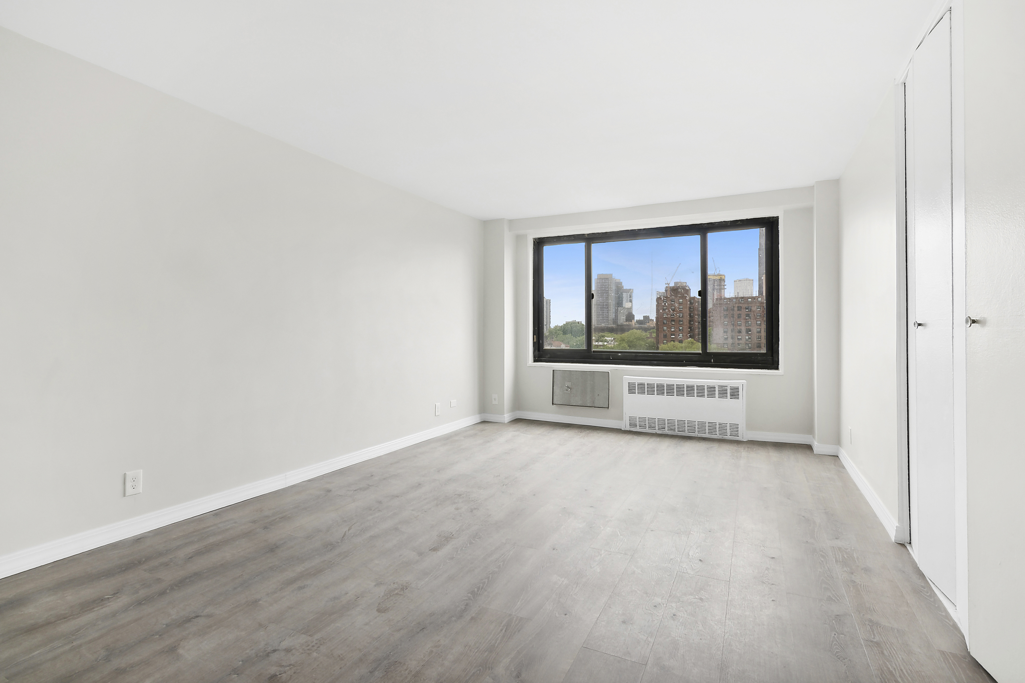 a view of a room with a window and hardwood floor