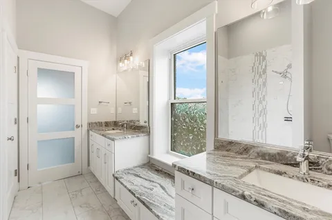 a bathroom with a granite countertop sink a mirror and a shower