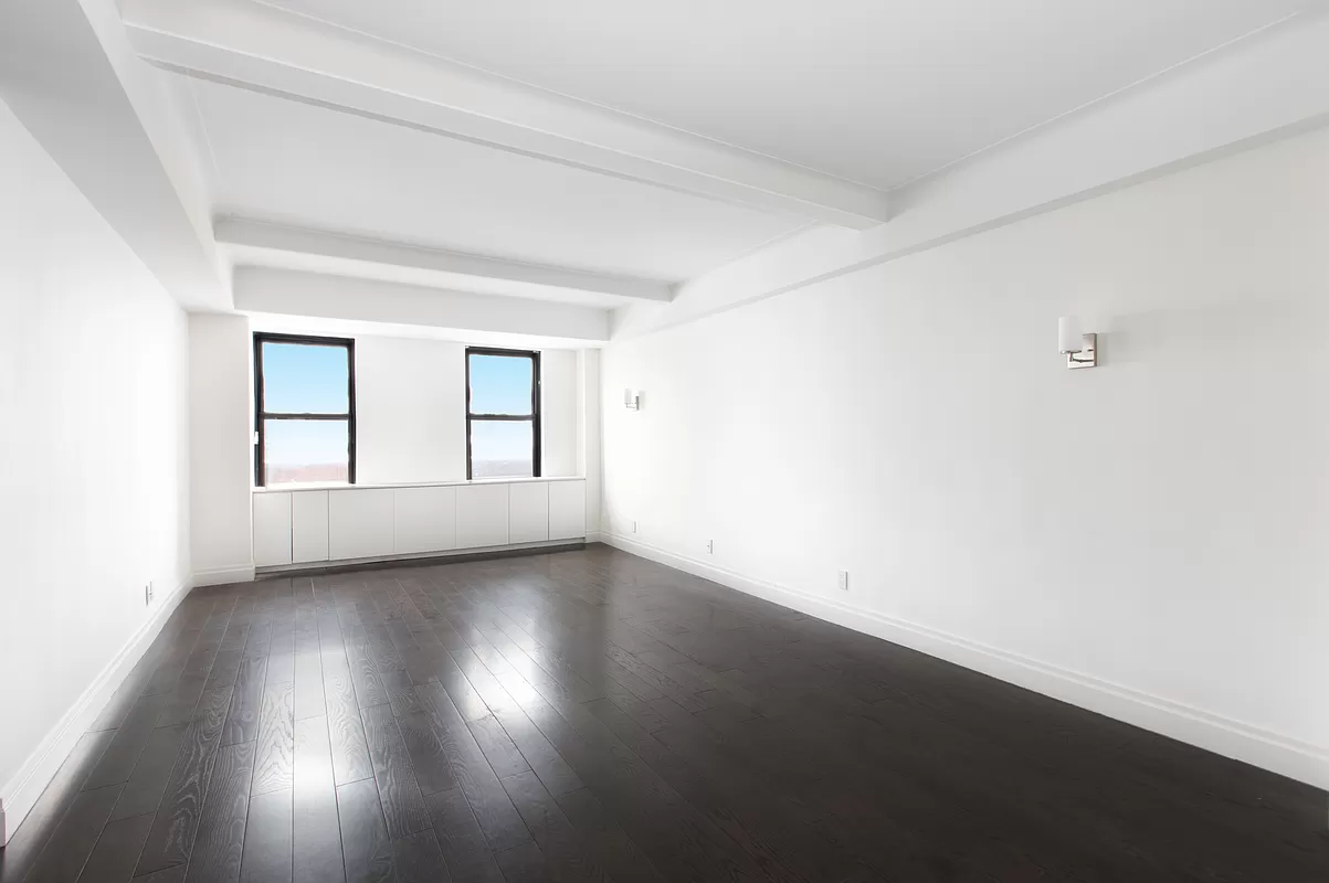 230 Riverside Drive, Unit 17D Manhattan, NY 10025 - Photo 5 of 18 an empty room with wooden floor and windows