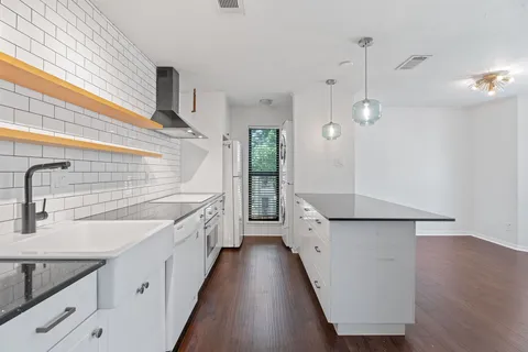 a kitchen with granite countertop white cabinets and wooden floor