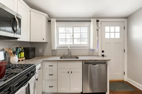 a kitchen with granite countertop a sink stove top oven and cabinets