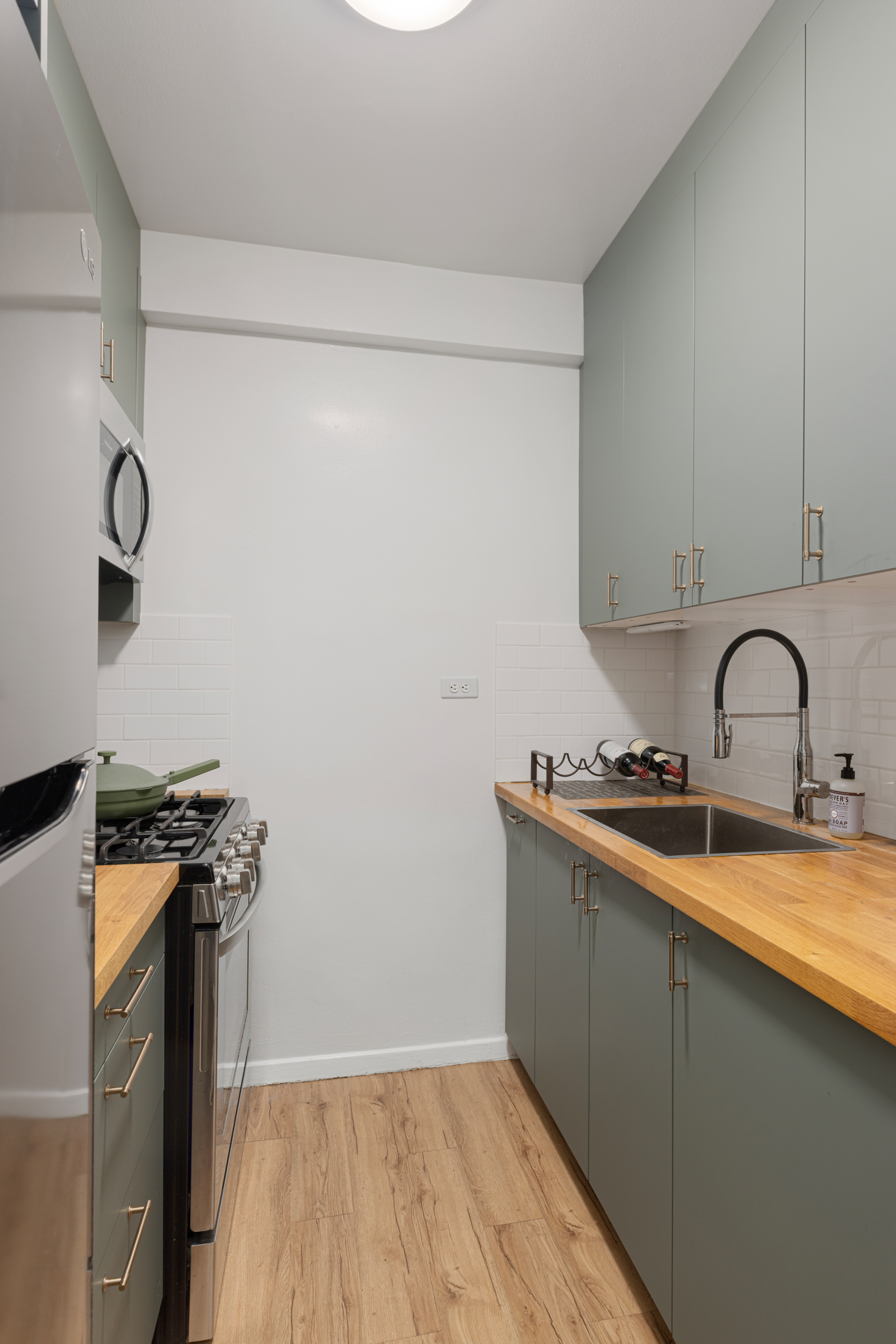 345 West 58th Street, Unit 4Y Manhattan, NY 10019 - Photo 8 of 12 a view of a kitchen with sink wooden floor and electronic appliances