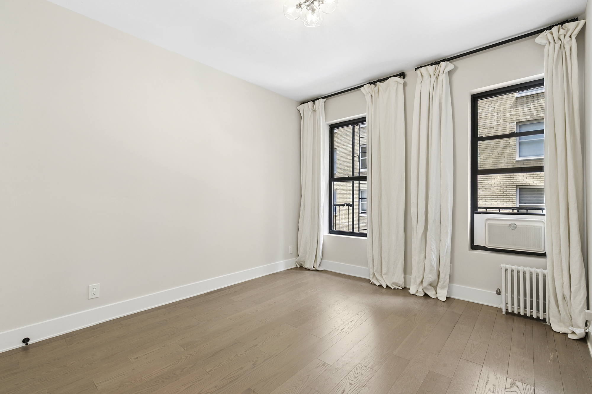 211 West 88th Street, Unit 2A Manhattan, NY 10024 - Photo 5 of 8 an empty room with wooden floor and windows